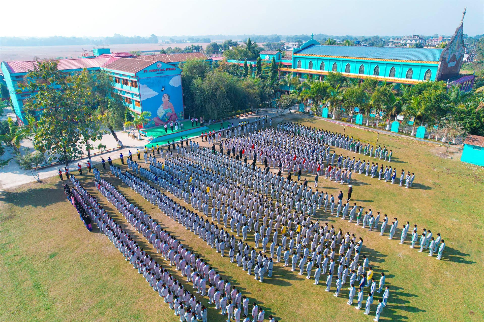 Aerial view of St. John's Higher Secondary School campus, with students assembled on the grounds — a live Academica ERP deployment
