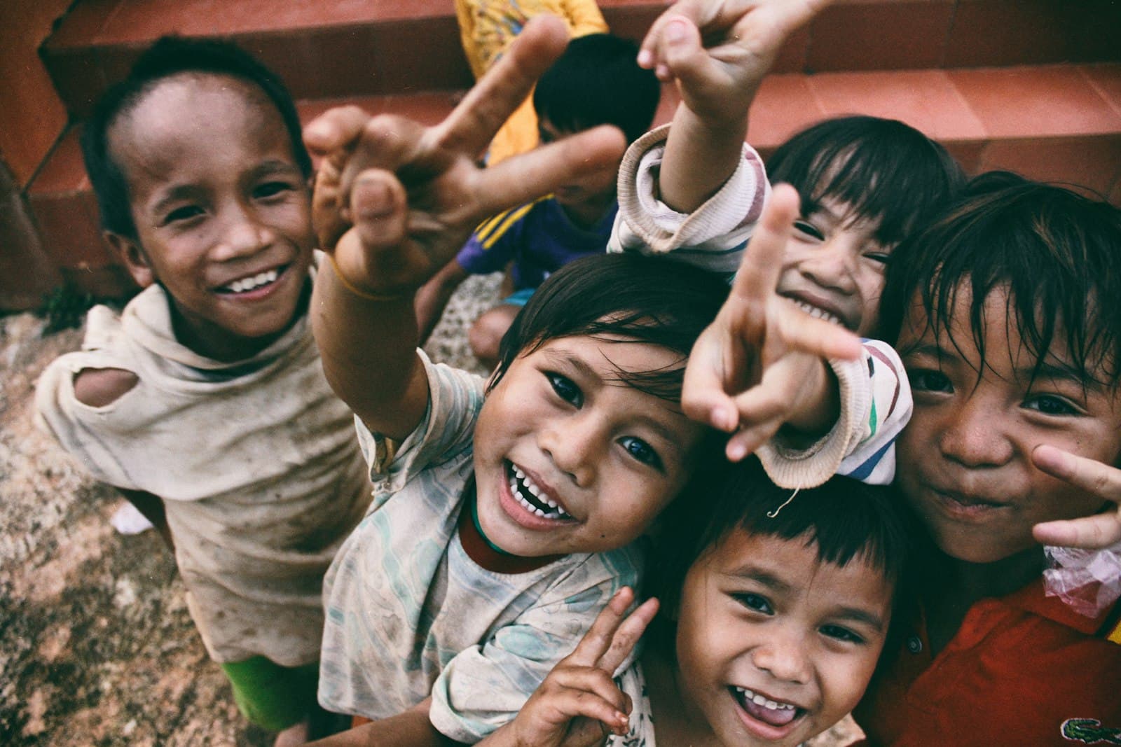 Smiling village children reaching their hands toward the camera, full of hope and joy